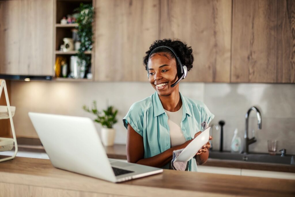 Smiling woman working remotely while doing household chores